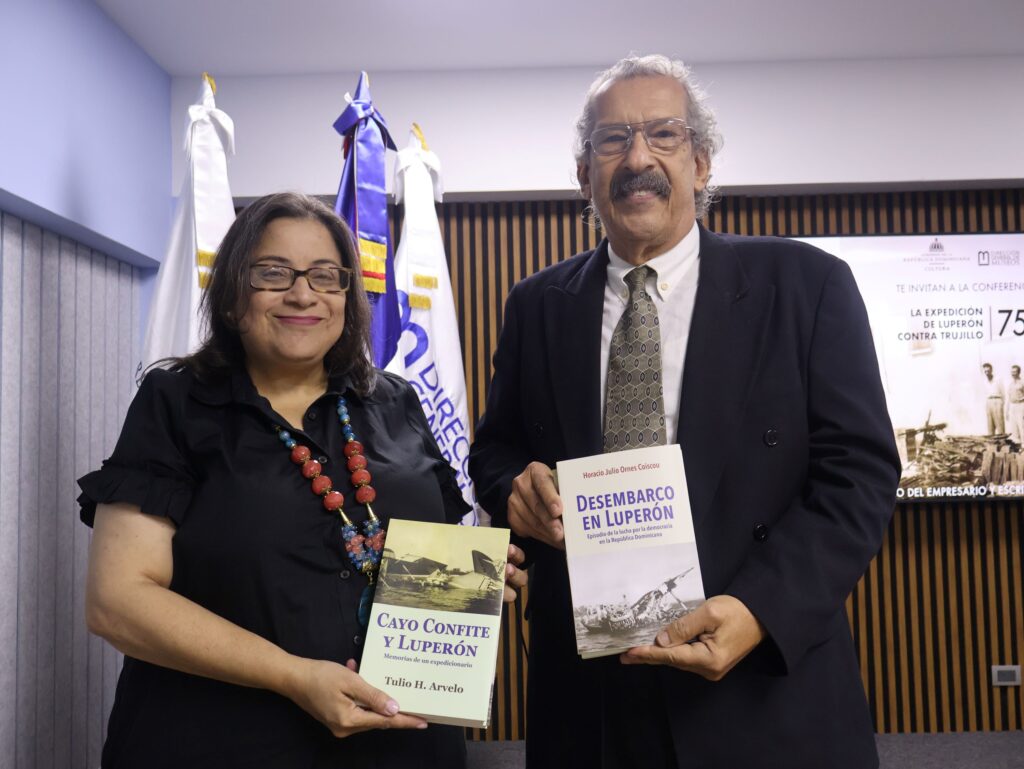 Luisa De Peña Díaz hace entrega a José G. Guillermo Sánchez de dos ejemplares de la obra reeditada con motivo de la conmemoración del 75 aniversario de la Expedición de Luperón.